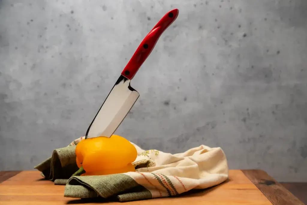 A santoku knife stuck in a yellow pepper.