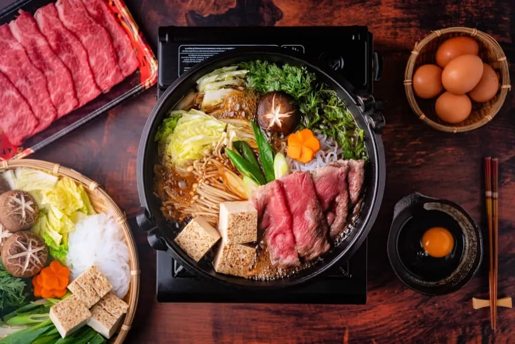 A pot of sukiyaki featuring meat and vegetables in a simmering pot.