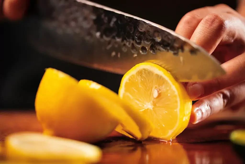 Someone slicing a lemon with a Japanese kitchen knife.
